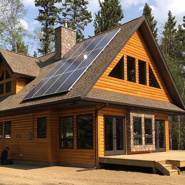 photo of a log cabin with solar panels on the roof
